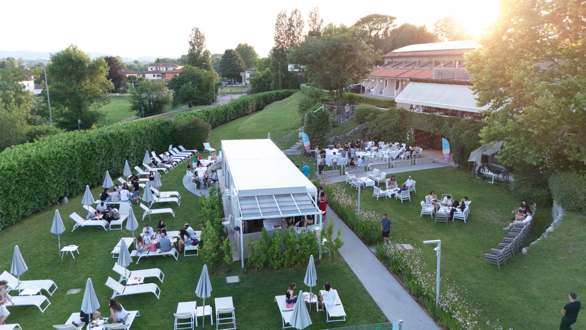 Vista dall'alto del giardino Meat Eat con tavoli e lettini al tramonto